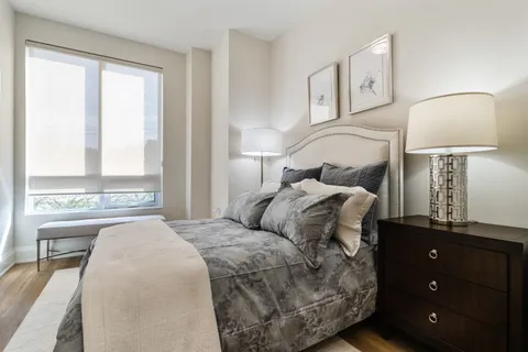 Bedroom with a grey bedspread and bedside tables beside a window