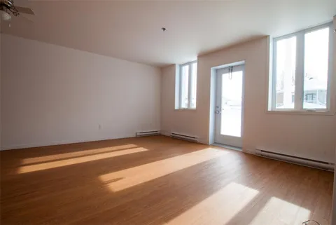 Empty room with wood flooring, windows and a glass door
