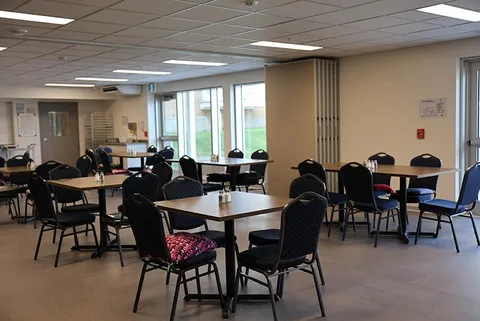 Dining room with square tables, black chairs and large windows