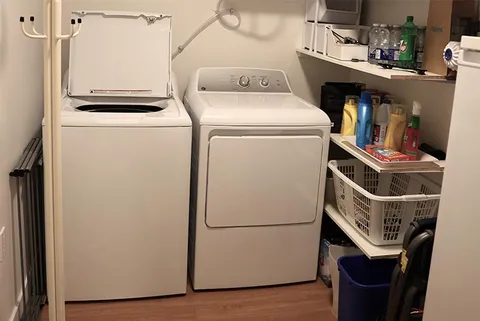 Laundry area with a washer, dryer and shelves of supplies