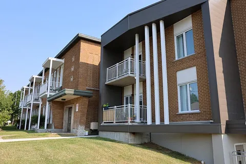 Brick building and white balconies viewed across a lawn