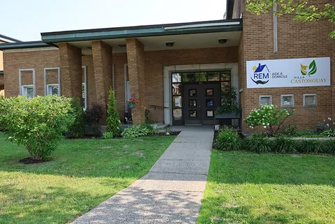 Entrance doors in a brick building beside a lawn and flower beds