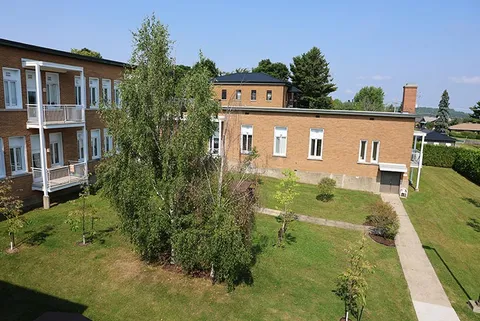 Brick buildings around a lawn with trees and a paved path