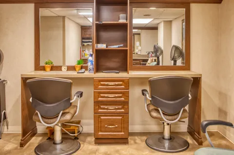 Hair salon with styling chairs, mirrors and wood cabinets.