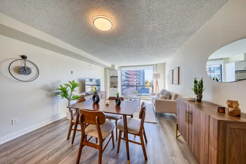 Suite dining and living area with a wooden table, armchairs and a large window.