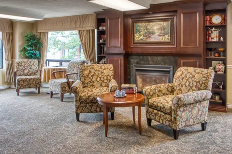 Fireside lounge with upholstered chairs, bookcases and a wooden fireplace surround.