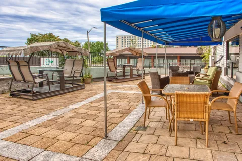 Paved patio with wicker seating, canopy shade and covered swings.