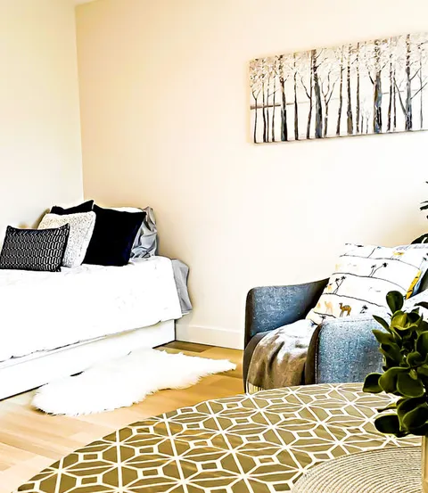 Room with a bed, armchair, patterned rugs and a picture of trees