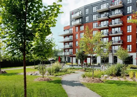 Residence building with balconies beside lawns, planted borders and paved paths