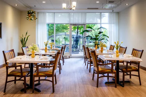 Dining room with set tables, chairs, flowers and large windows