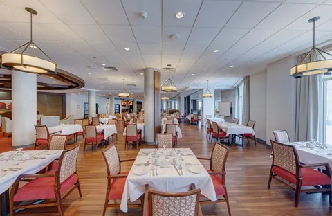 Dining room with set tables and upholstered chairs beside windows