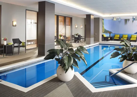 Indoor swimming pool with handrails and a tropical beach mural