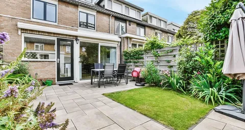 Garden courtyard with a paved patio, lawn and flower beds beside the building