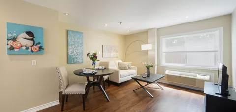 Sitting area with a white sofa, dining table and bird artwork