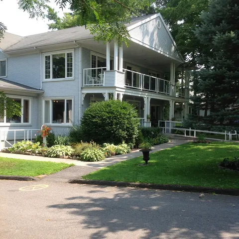 White residence exterior with balconies beside a lawn and driveway