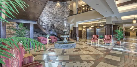 Lobby with a fountain, staircase, elevators and seating.