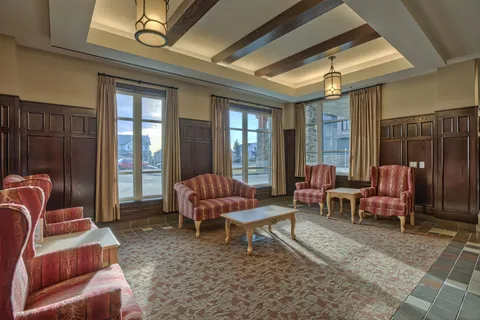 Lounge with armchairs and wood-panelled walls.