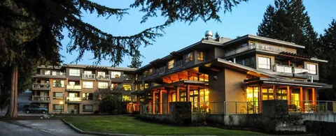 Multi-storey building and glass dining pavilion illuminated at dusk