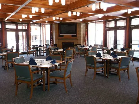 Dining room with set tables, upholstered chairs and a large dark television