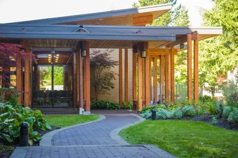 Curving paved path leading to a covered glass entrance