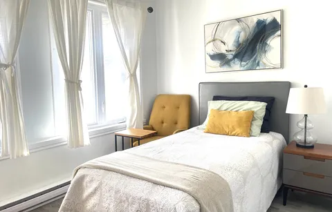Bedroom with a single bed, yellow armchair and abstract wall art