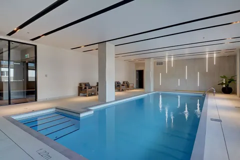 Indoor swimming pool with tiled walls, windows and a handrail