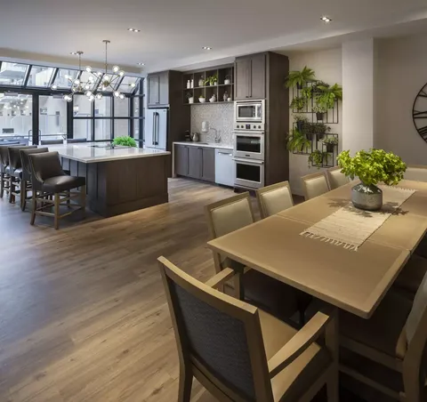 Room with a dining table, kitchen island, cupboards and ovens