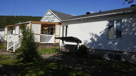 Residence exterior with white siding and a covered wooden porch.