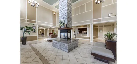 Tall lobby with a stone fireplace, tiled floor and cushioned benches