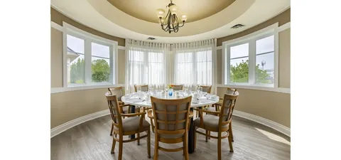Round dining table with wooden chairs and windows on three sides
