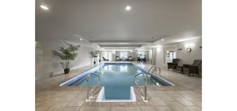 Indoor pool with steps, metal handrails and chairs along the walls