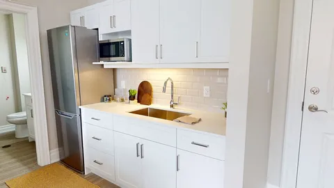 Suite kitchenette with white cabinets and stainless-steel appliances