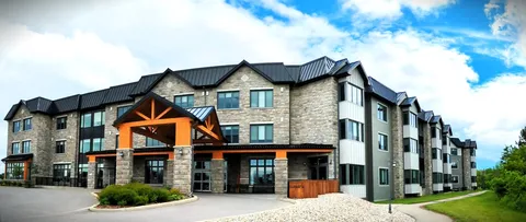 Residence exterior with stone walls, timber entrance beams and a paved driveway.