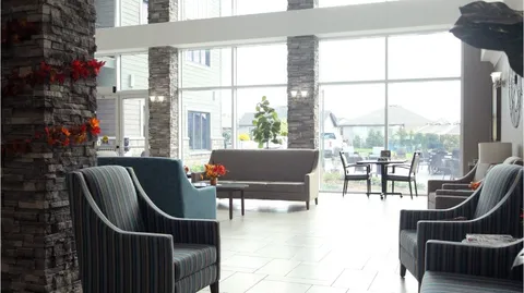 Atrium sitting area with armchairs and tall windows.