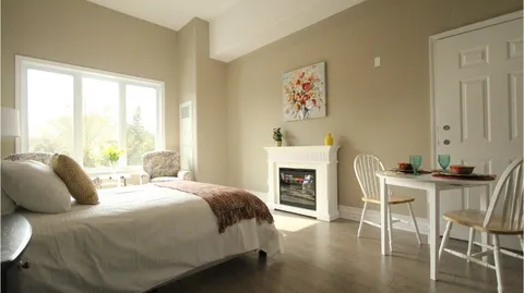 Studio suite with a bed, fireplace, dining table and window.