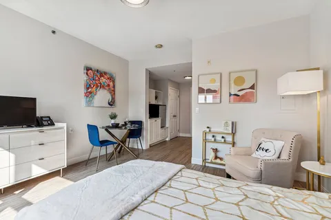 Bedroom with a patterned bedspread, armchair, television and small dining table