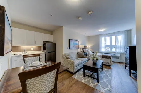 Suite with a kitchenette, dining table, sofa and large windows