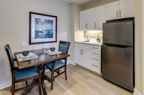 Kitchenette with white cabinets and a small dining table