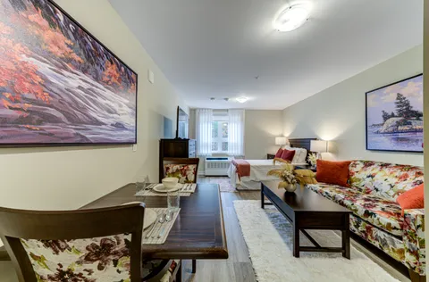 Room with a bed, floral sofa, coffee table and landscape pictures
