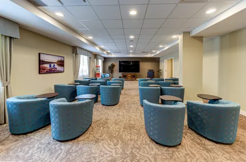 Room with rows of blue armchairs and a television at the far end