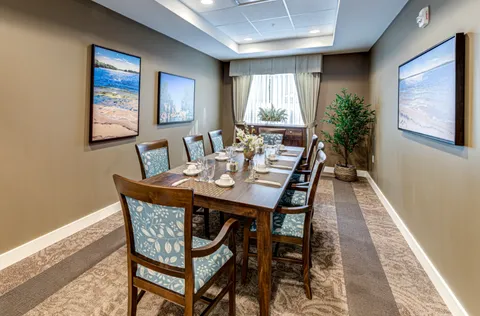 Dining table with upholstered chairs and coastal landscape pictures on the walls