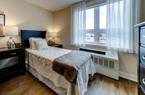 Bedroom with a single bed, bedside lamps and a large window