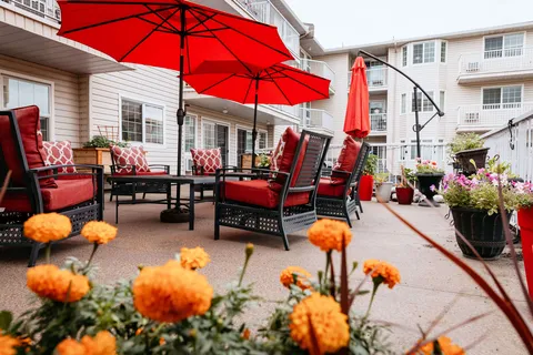 Patio with red umbrellas, cushioned chairs and potted flowers