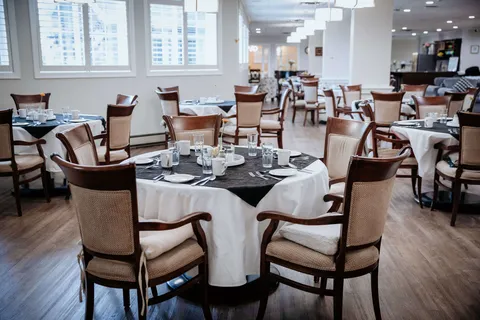 Dining room with round set tables, upholstered chairs and large windows
