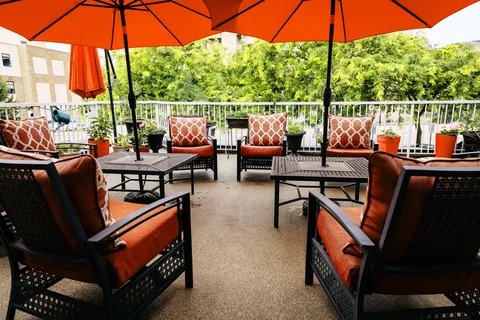 Outdoor seating under orange umbrellas beside a railing
