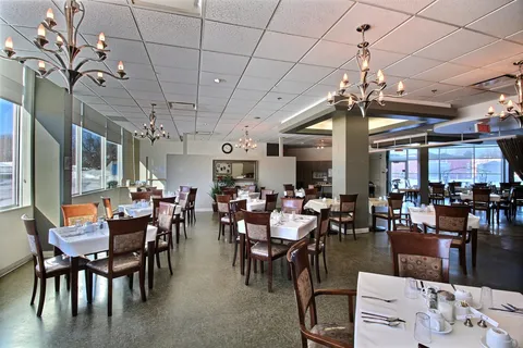 Dining room with set tables, wooden chairs, chandeliers and large windows