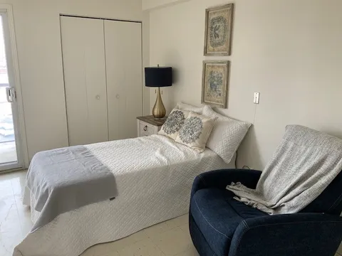 Bedroom with a single bed, blue armchair, lamp and double-door closet