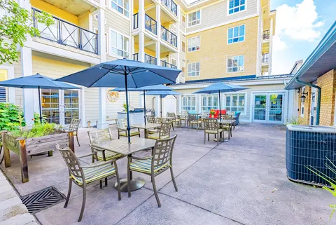 Courtyard patio with tables, chairs, blue umbrellas and raised planters