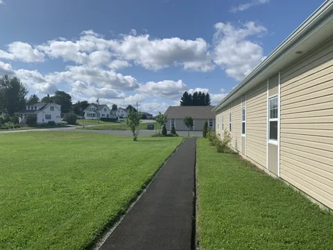 Side of the residence beside a lawn and paved path.