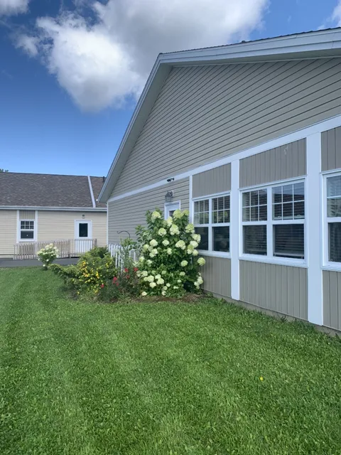 Residence windows above a flower bed and lawn.